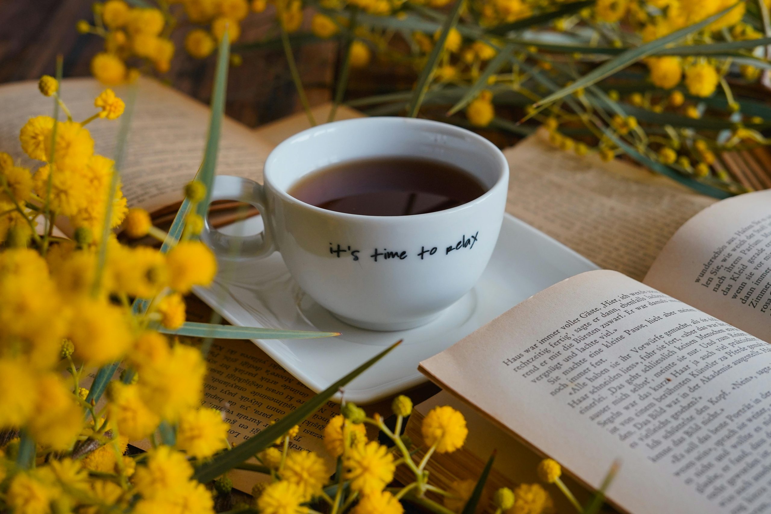 A relaxing tea moment surrounded by books and yellow flowers, creating a cozy reading atmosphere.